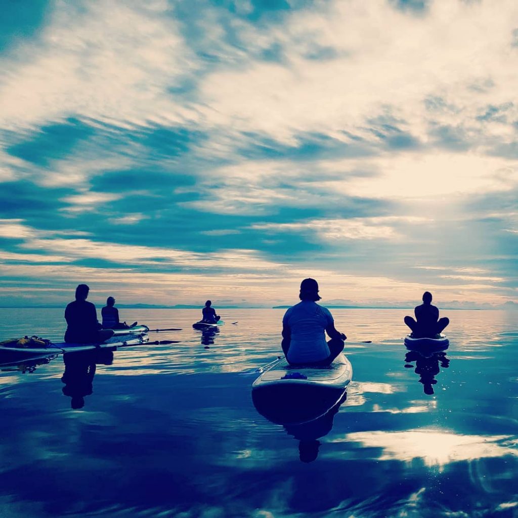 Silhouette Of A Yoga Trainer Balancing On The Water On The Paddle